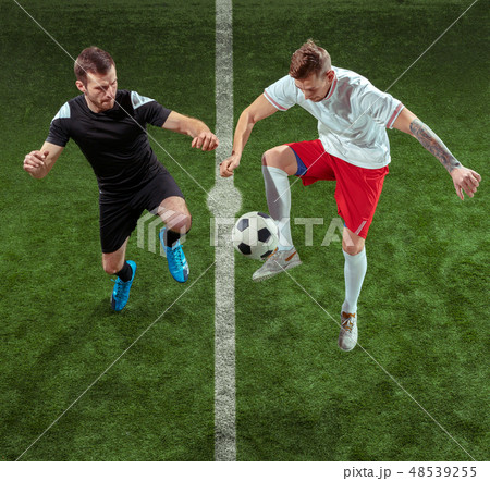 Football players tackling ball over green grass background 48539255