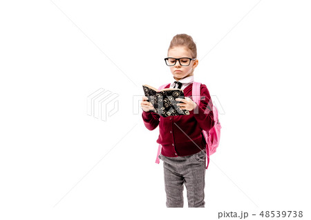 Child with schoolbag. Girl in white shirt and gray pants, rounded glasses, hold a book, school bag 48539738