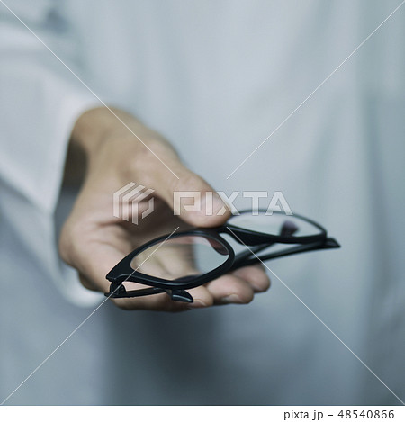 optician man bringing a pair of eyeglasses 48540866