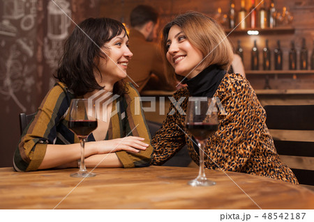 Two young female best friends relaxing with a glass of wine in a restaurant. Two young female best friends relaxing with a glass of wine in a restaurant. 48542187