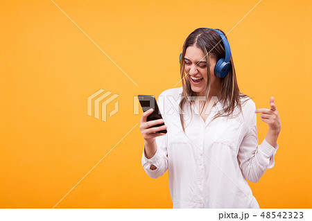 Beautiful girl browsing on her phone and listening music on her headphones Beautiful girl browsing on her phone and listening music on her headphones 48542323