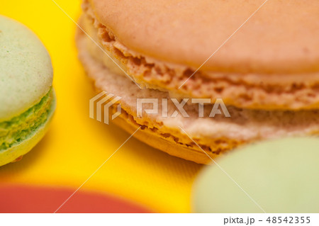 Close up big macaroon caramel flavour next to little macaroons over yellow background 48542355