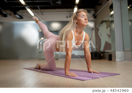 Blonde athlete girl standing on all fours on mat doing yoga. Blonde athlete girl standing on all fours on mat doing yoga. 48542960
