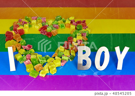 Multicolored pieces of dried pineapples are laid out in the shape of a heart, and the metal letters 48545205