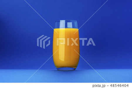 Glass of orange juice isolated on blue background with copy space Glass of orange juice isolated on blue background with copy space 48546404