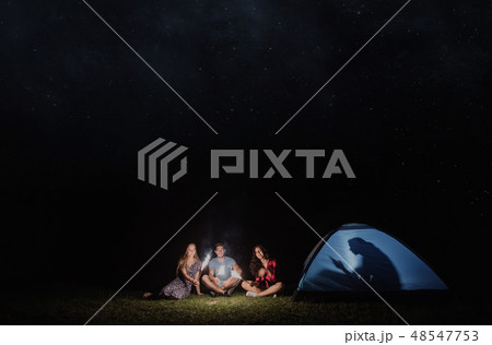 Friends with sparklers outdoors at dusk, one with smartphone, technology addiction. Friends with sparklers outdoors at dusk, one with smartphone, technology addiction. 48547753