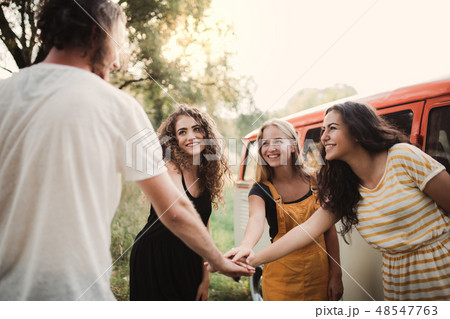 A group of young friends on a roadtrip through countryside, putting hands together. A group of young friends on a roadtrip through countryside, putting hands together. 48547763