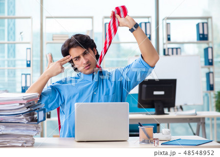 Handsome businessman unhappy with excessive work in the office  48548952