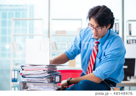 Handsome businessman unhappy with excessive work in the office  48548976