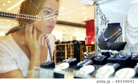 close-up, woman looks at jewelry through a glass showcase. 48549042