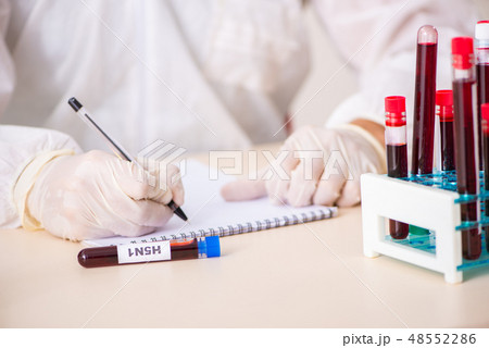 Young handsome lab assistant testing blood samples in hospital  48552286