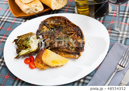 Cabeza de cordero - spanish dish. Lamb head with artichoke, tomatoes and potatoes 48554352