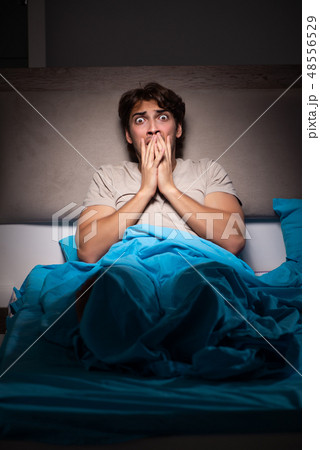 Young man scared in his bed having nightmares 48556529