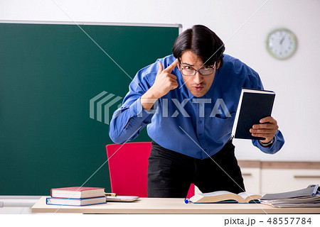 Young male teacher in front of chalkboard Young male teacher in front of chalkboard 48557784