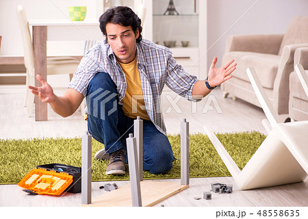 Young handsome man repairing chair at home  48558635