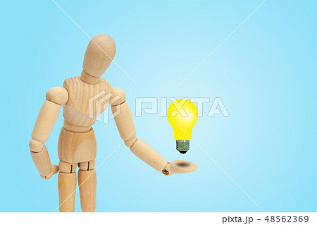 Wooden figure mannequin holding light bulb in hand Wooden figure mannequin holding light bulb in hand 48562369
