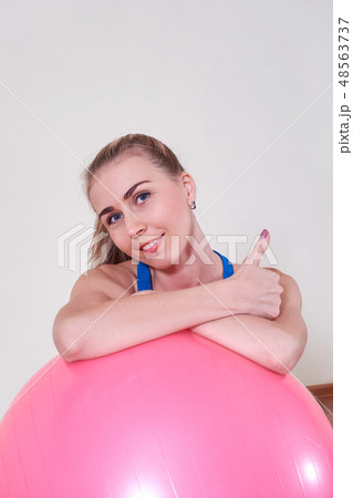 Athletic woman makes exercises on a fitness ball , indoors gym. Athletic woman makes exercises on a fitness ball , indoors gym. 48563737