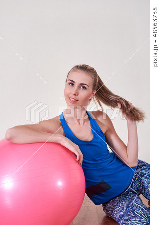 Athletic woman makes exercises on a fitness ball , indoors gym. Athletic woman makes exercises on a fitness ball , indoors gym. 48563738
