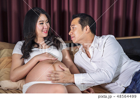 Pregnant women with her husband feeling happy on bed 48564499