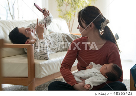 赤ちゃんを抱く母親とスマホに夢中な父親 ワンオペ育児 赤ちゃんを抱く母親とスマホに夢中な父親 ワンオペ育児 48565422