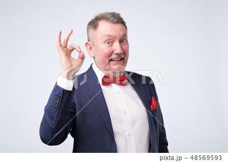 Senior man in elegant blue suit showing OK sign Senior man in elegant blue suit showing OK sign 48569593