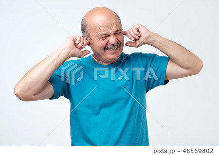 Senior hispanic bald guy plugging ears with finger Senior hispanic bald guy plugging ears with finger 48569802