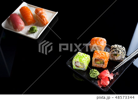 Large sushi sets with lots of sushi, roll . Stylish sushi sets on a black ceramic plane and table 48573344