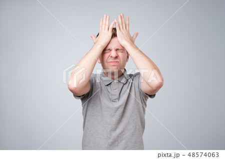 man holding hands on head and closing his eyes 48574063