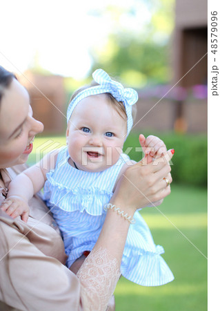 Closeup happy mother holding little female child in blue dress. 48579096