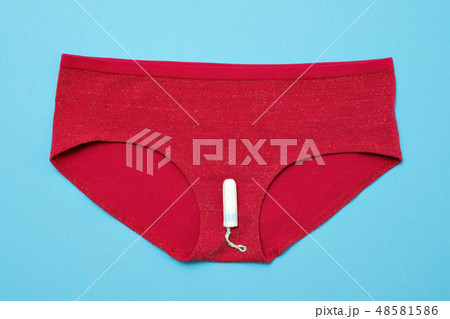 White tampon on red pants on colored background. 48581586