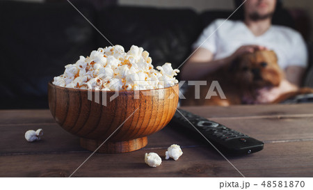 Wooden bowl with salted popcorn and TV remote. Wooden bowl with salted popcorn and TV remote. 48581870