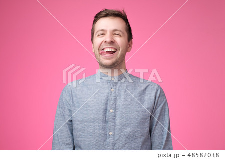 attractive guy in blue shirt showing tongue 48582038