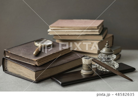 Several of antic books, set of old stationery, wooden pen, inkwell, magnifier close-up, vintage Several of antic books, set of old stationery, wooden pen, inkwell, magnifier close-up, vintage 48582635
