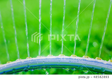 Lawn sprinkler spaying water over green grass 48582893
