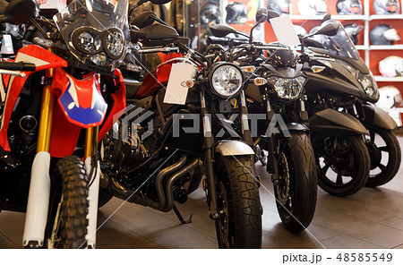 View of range new motorcycles parked in showroom for sale 48585549