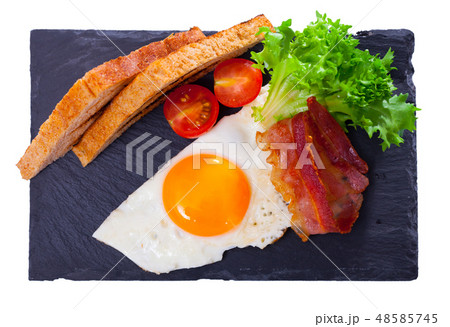 Fried eggs with bacon, bread and vegetable Fried eggs with bacon, bread and vegetable 48585745