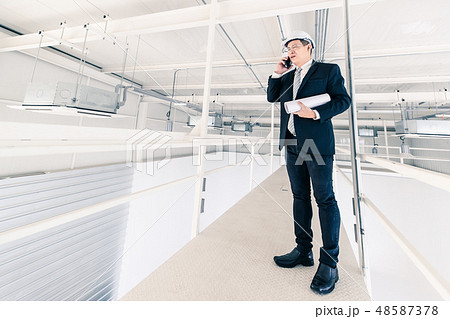 Asian engineer hold blueprint and use cellphone.. Asian engineer hold blueprint and use cellphone.. 48587378