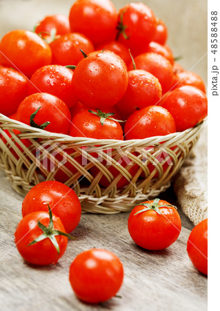 Red tomatoes in a wicker basket on an wooden table 48588488
