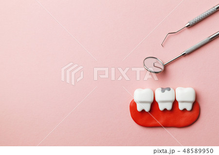 Healthy white teeth and tooth with caries on pink background  and dentist tools mirror, hook. Copy 48589950