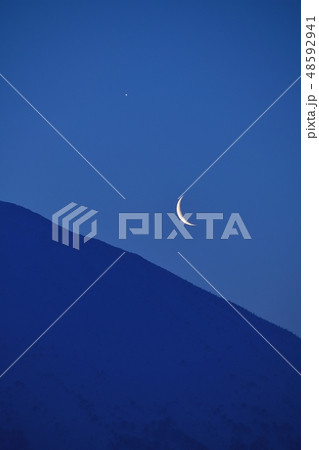 早春の北海道ニセコ町から羊蹄山（蝦夷富士）の稜線から三日月と明けの明星が昇る夜明けの風景を撮影 48592941