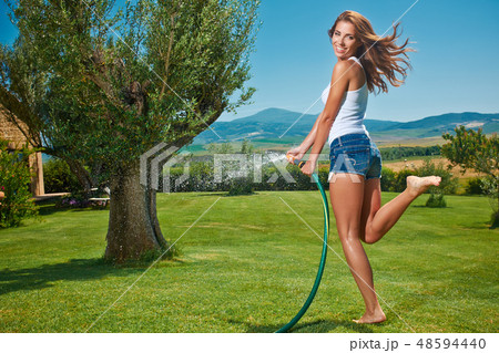 Beautiful young woman having fun in summer garden with garden ho Beautiful young woman having fun in summer garden with garden ho 48594440
