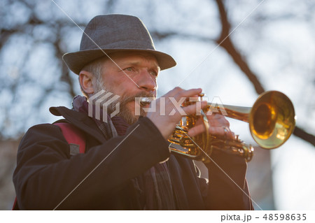 elderly musician plays in the street on a trumpet  48598635