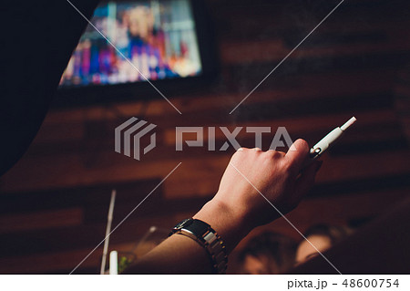 IQOS heat-not-burn tobacco product technology. Woman holding e-cigarette in his hand before smoking. IQOS heat-not-burn tobacco product technology. Woman holding e-cigarette in his hand before smoking. 48600754