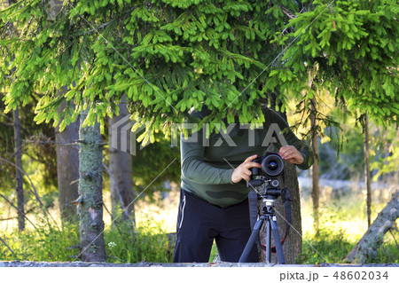 The photographer sets up the camera and hides 48602034