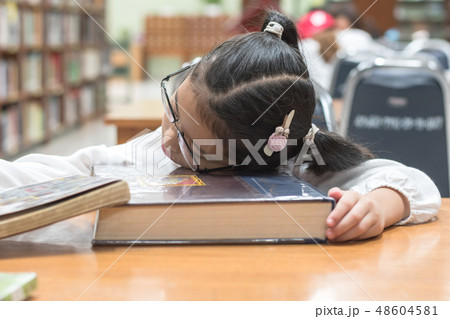 Kid student studying hard feeling tired in library Kid student studying hard feeling tired in library 48604581