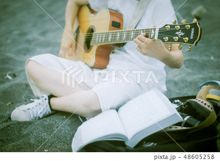 海でギターを弾き語りする女の子 48605258