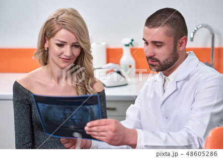 Caucasian male dentist explaining to female patient the x-ray Caucasian male dentist explaining to female patient the x-ray 48605286