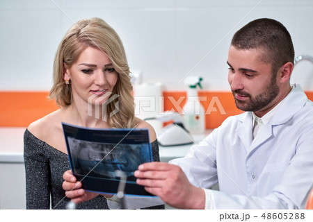 Caucasian male dentist explaining to female patient the x-ray Caucasian male dentist explaining to female patient the x-ray 48605288
