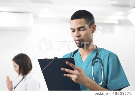 Men in a cyan colored dental coat taking notes 48605576