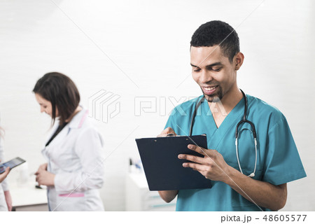 Men in a cyan colored dental coat taking notes 48605577